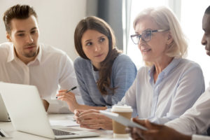 Focused young interns making notes listening to old female manager